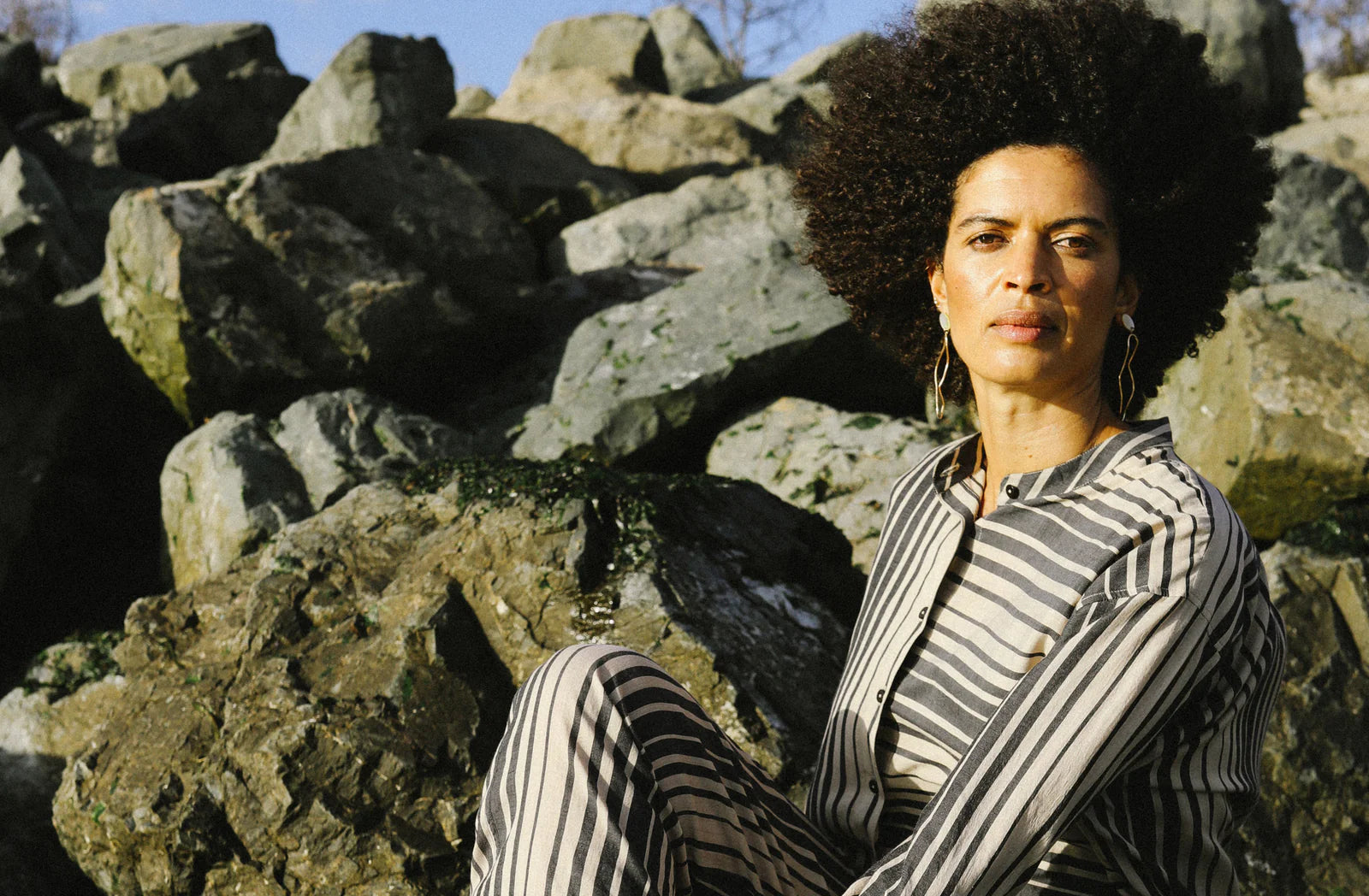 一名妇女在岩石地形上展示可持续时尚服装