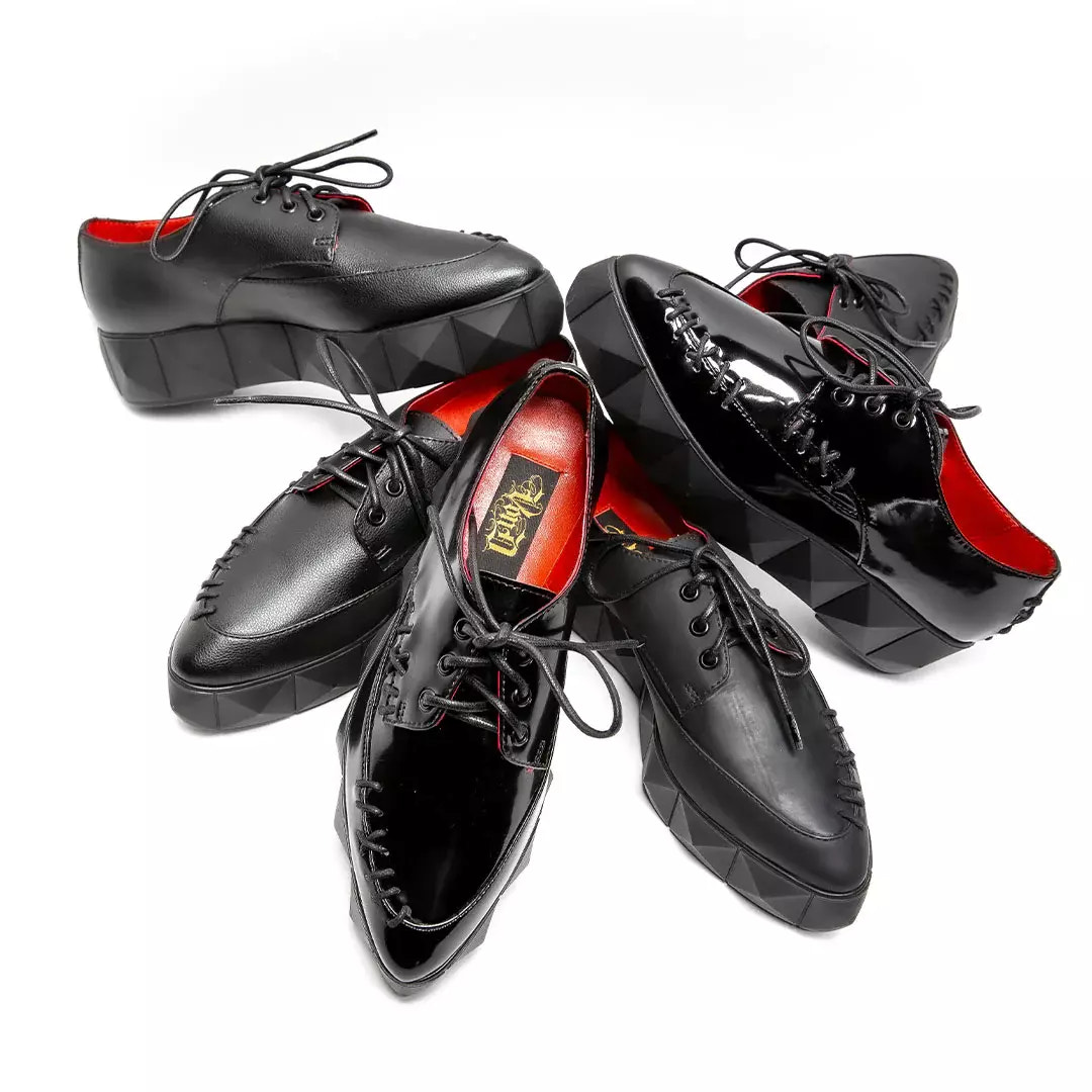 Multiple black loafer-style vegan leather shoes stacked on one another in a circular pattern.