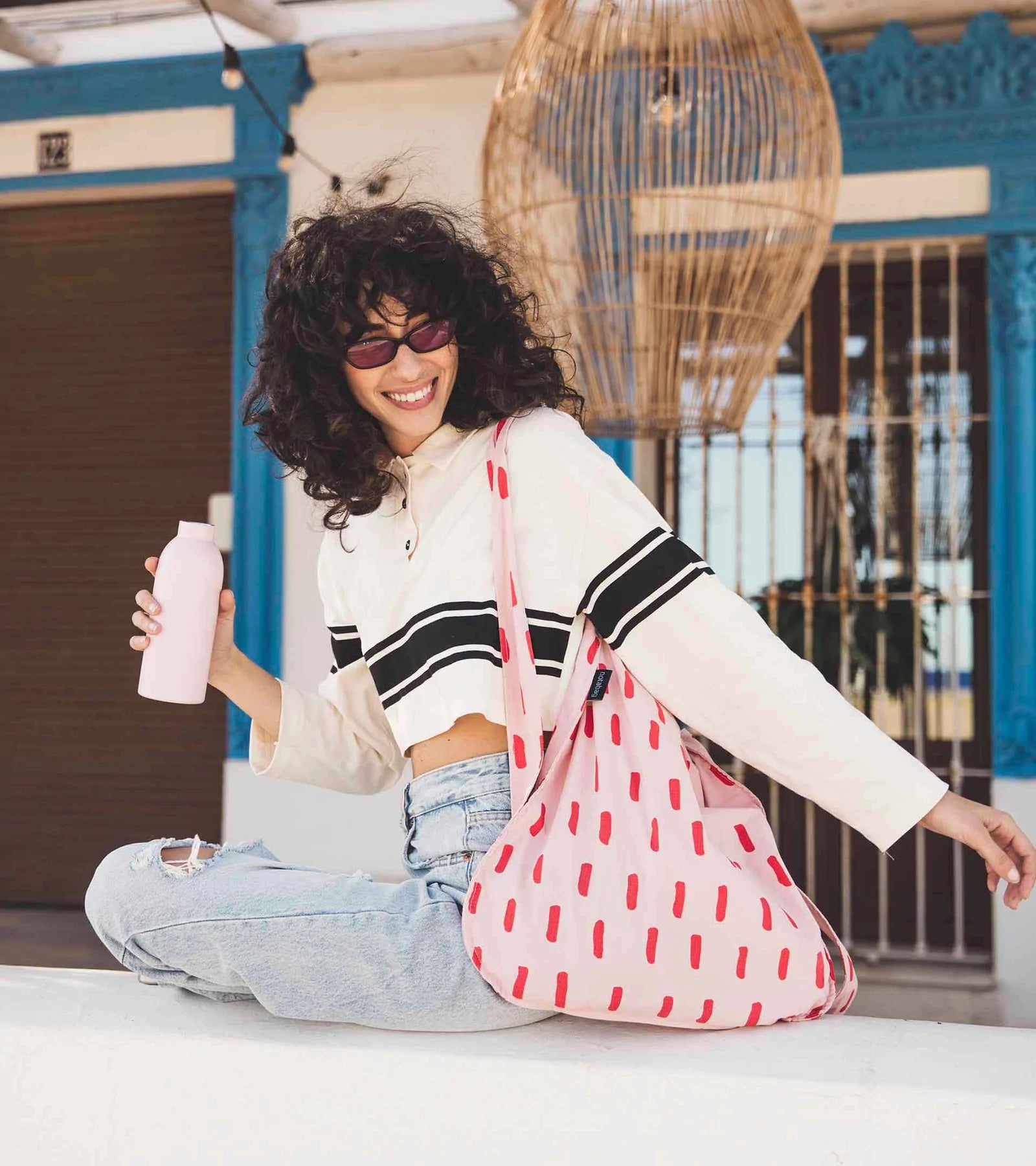 A person models a red and white printed tote bag
