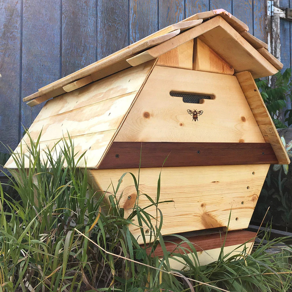 A wooden beehive surrounded by grass