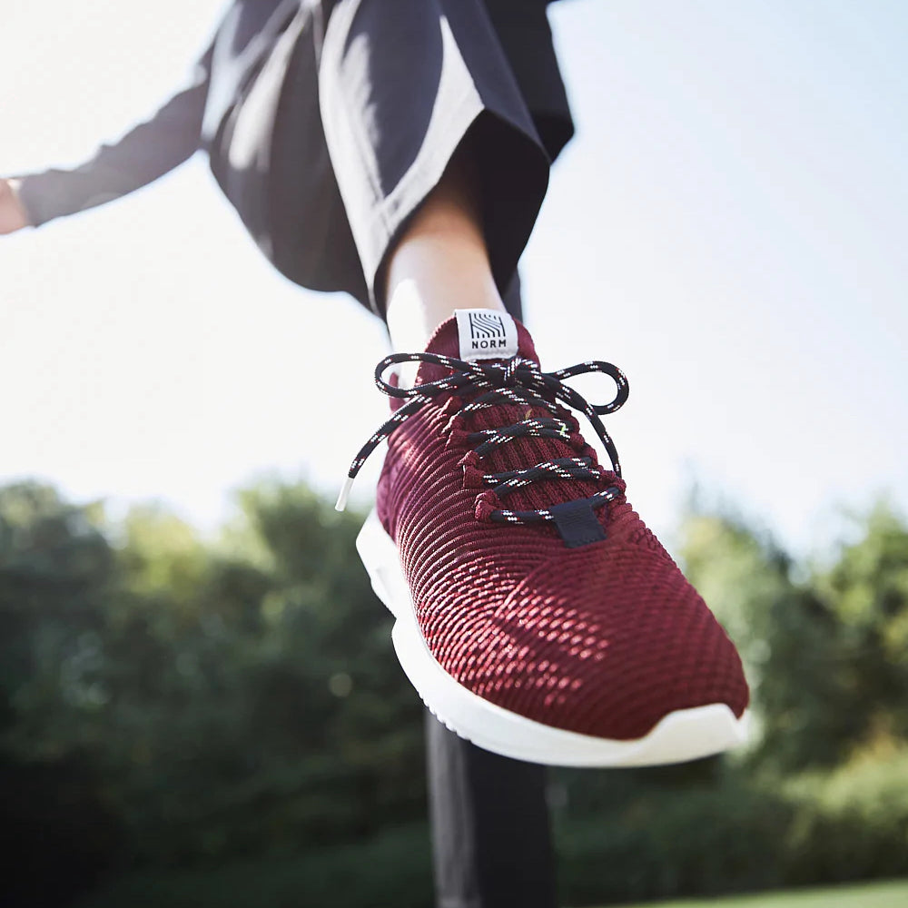 Close detail of a person's foot modelling a dark red sneaker