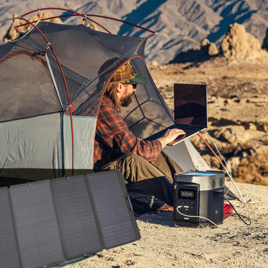 Rustic scene of a person in a tent using a laptop that's powered by a portable solar generator