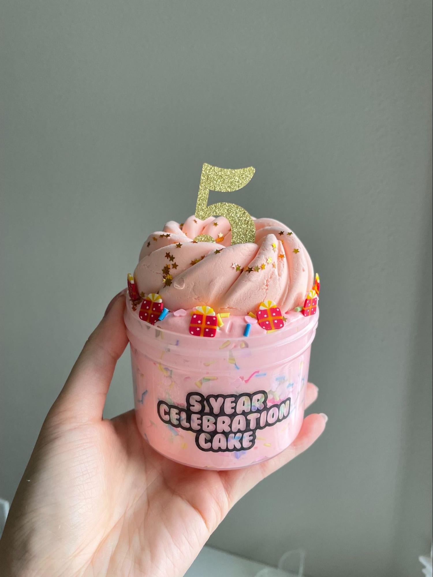 粉色黏液装在一个容器里,上面突出了数字5,象征着五周年纪念