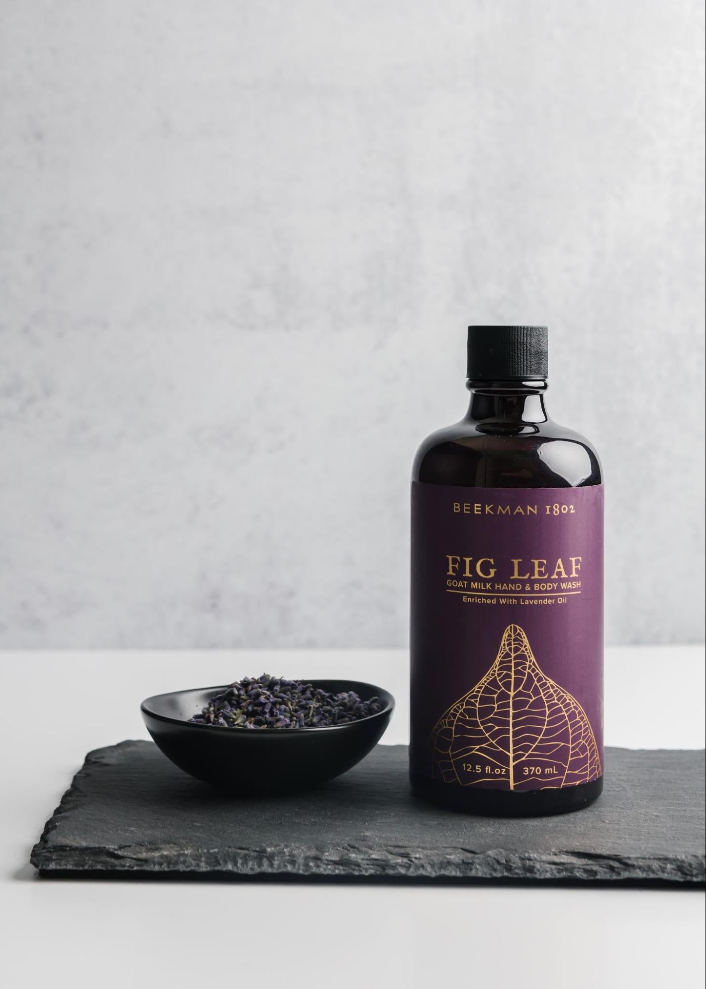 The same photo of a bottle and bowl of fig leaves, only now the bottle is on the right casting a shadow onto the fig leaves on the left