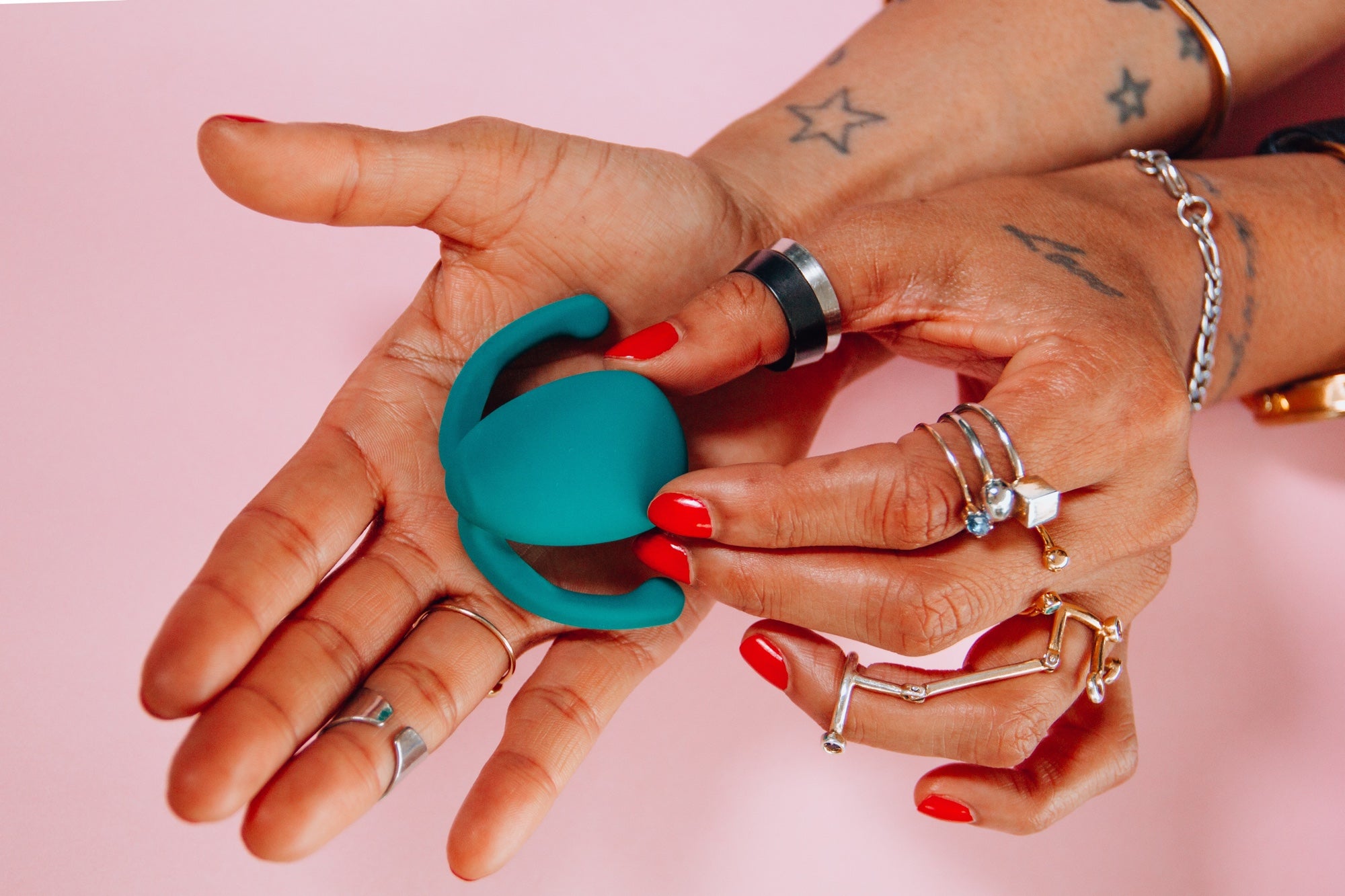 手拿着一个粉红色背景的蓝色振动器性玩具